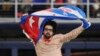 El escritor y periodista Carlos Manuel Alvarez se lanza al terreno en el LoanDepot Park de Miami con la bandera cubana en alto, en protesta contra el régimen de La Habana. (AP/Marta Lavandier)
