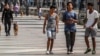 Jóvenes caminan por el Paseo del Prado mientras miembros de la policía patrullan en La Habana, el 11 de julio de 2022. (AP Foto/Ramon Espinosa)