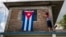 Una mujer adorna su casa con una bandera cubana / Foto: AFP